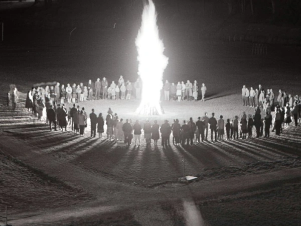 Um ein großes Feuer haben sich, in einem Kreis, viele Menschen versammelt.