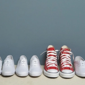 Ein Paar roter Schuhe steht in einer Reihe weißer Schuhe.