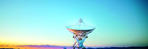 Eine Riesige Satellitenschüssel steht im Sonnenaufgang.