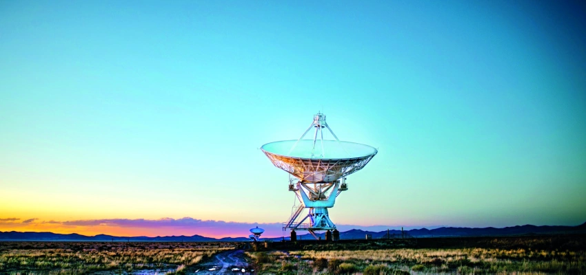 Eine Riesige Satellitenschüssel steht im Sonnenaufgang.