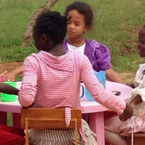 Eine Kindergruppe sitzt am Kaffeetisch.