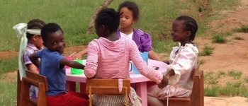 Eine Kindergruppe sitzt am Kaffeetisch.