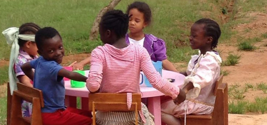 Eine Kindergruppe sitzt am Kaffeetisch.