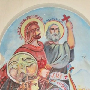 Eine Wandmalung zeigt einen Kreuzträger und einen Krieger mit Heiligenscheinen. Davor kniet ein Bogenschütze.