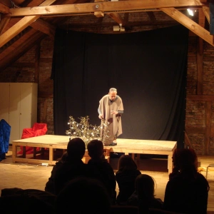 Ein Mann steht alleine auf einer Bühne und spielt eine Szene.