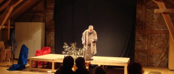 Ein Mann steht alleine auf einer Bühne und spielt eine Szene.