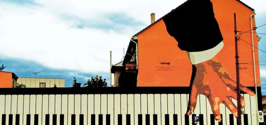 Auf ein Gebäude sind Hände gemalt, die Klavier spielen.