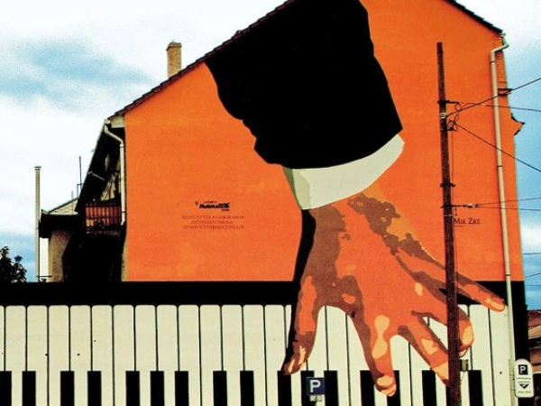 Auf ein Gebäude sind Hände gemalt, die Klavier spielen.