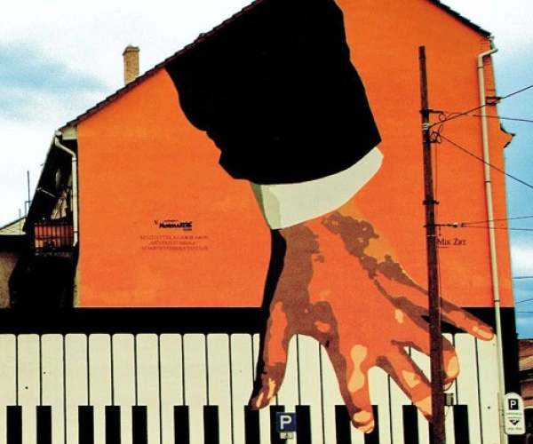 Auf ein Gebäude sind Hände gemalt, die Klavier spielen.