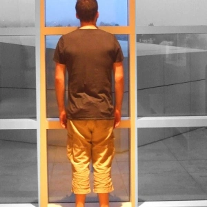 Ein Mann steht vor einer Glaswand. Das Bild ist Schwarz-weiß, nur sein Bildausschnitt ist bunt.