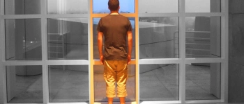 Ein Mann steht vor einer Glaswand. Das Bild ist Schwarz-weiß, nur sein Bildausschnitt ist bunt.