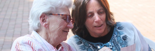 Eins alte Frau zeigt einer jüngeren etwas auf einem Foto.