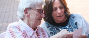 Eins alte Frau zeigt einer jüngeren etwas auf einem Foto.