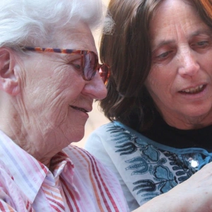 Eins alte Frau zeigt einer jüngeren etwas auf einem Foto.