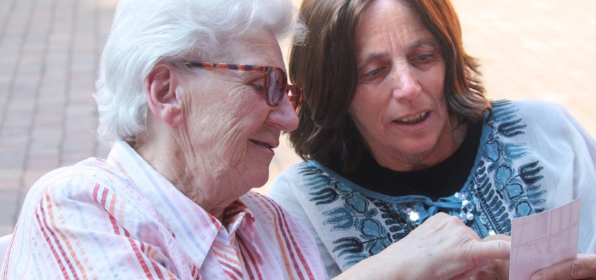 Eins alte Frau zeigt einer jüngeren etwas auf einem Foto.