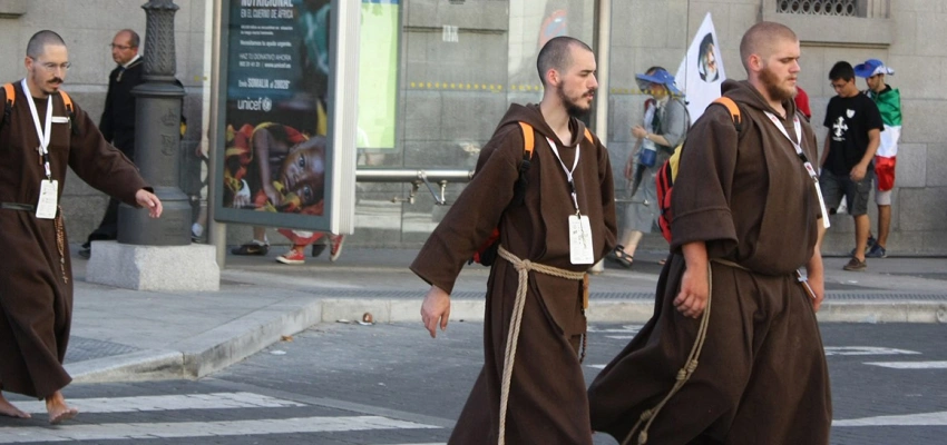 In kutten gekleidete Männer gehen über einen Zebrastreifen.