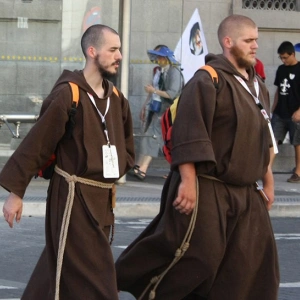 In kutten gekleidete Männer gehen über einen Zebrastreifen.