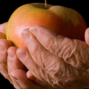 Zwei Hände umfassen einen Apfel.