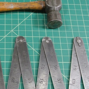Ein Hammer und ein Zollstock liegen auf einer Unterlage.