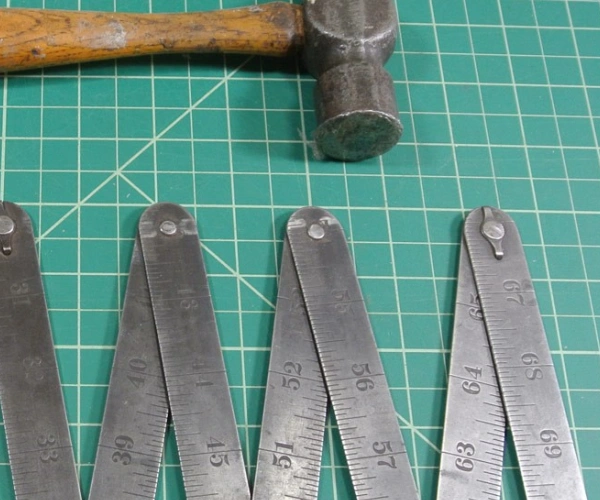 Ein Hammer und ein Zollstock liegen auf einer Unterlage.