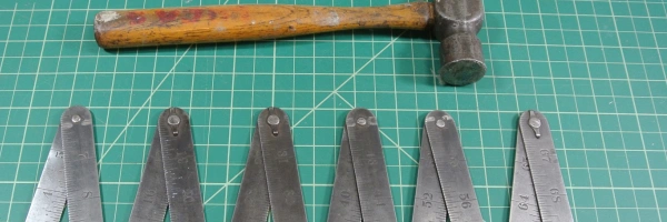Ein Hammer und ein Zollstock liegen auf einer Unterlage.