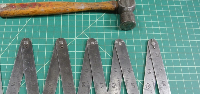 Ein Hammer und ein Zollstock liegen auf einer Unterlage.