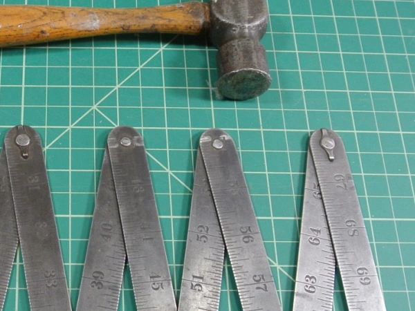 Ein Hammer und ein Zollstock liegen auf einer Unterlage.