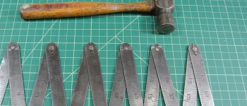 Ein Hammer und ein Zollstock liegen auf einer Unterlage.