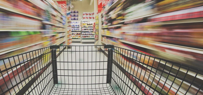 Ein Einkaufswagen in einem Supermarktgang.
