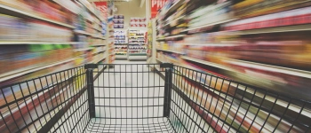 Ein Einkaufswagen in einem Supermarktgang.