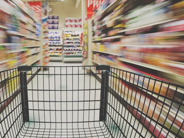 Ein Einkaufswagen in einem Supermarktgang.