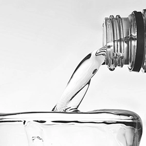 Wasser fließt aus einer Flasche in ein bereits überlaufendes Glas.