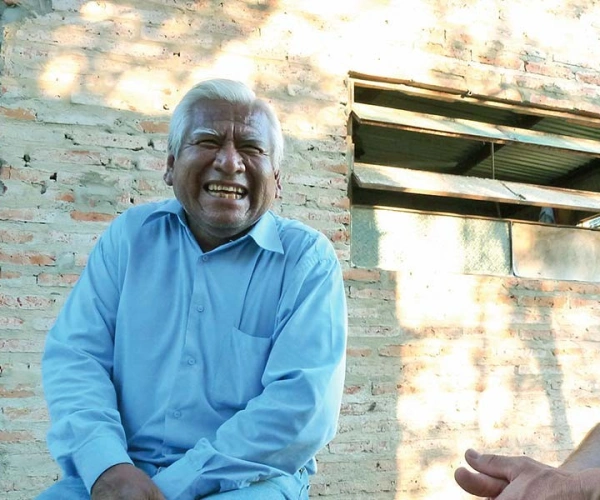 Zwei sitzende Männer lachen gemeinsam neben einem Haus in Argentinien