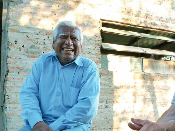 Zwei sitzende Männer lachen gemeinsam neben einem Haus in Argentinien