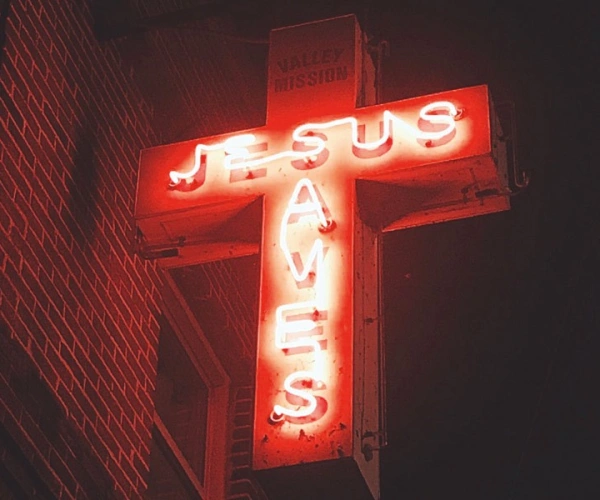 Ein Kreuz aus Neonröhren mit Schriftzug 