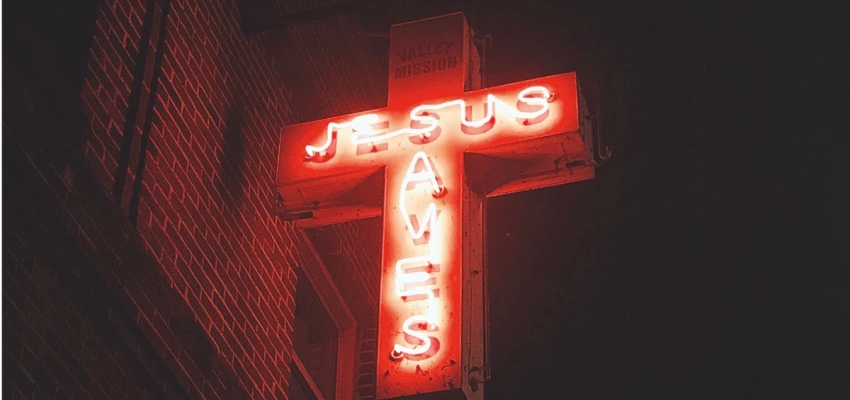 Ein Kreuz aus Neonröhren mit Schriftzug 