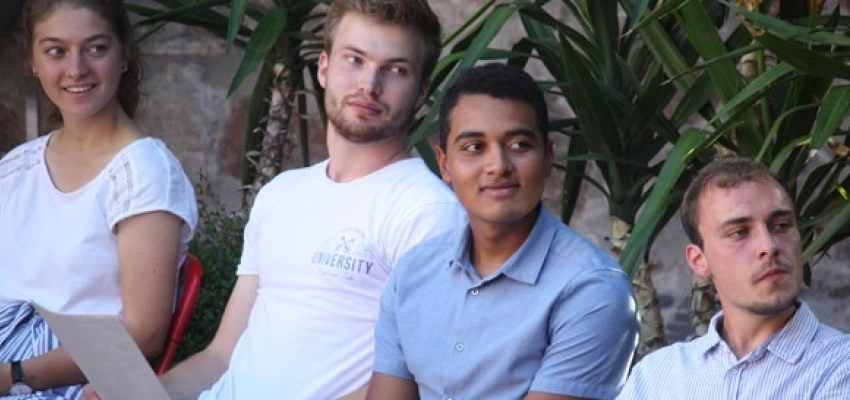 Vier sitzende Jugentliche gucken in die gleiche Richtung