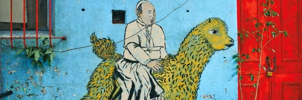 Buntes Gemälde eines Bischofs an einer blauen Hauswand