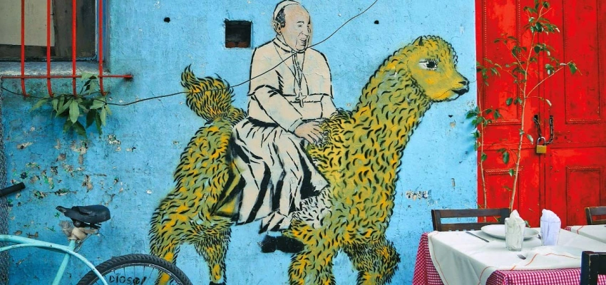 Buntes Gemälde eines Bischofs an einer blauen Hauswand