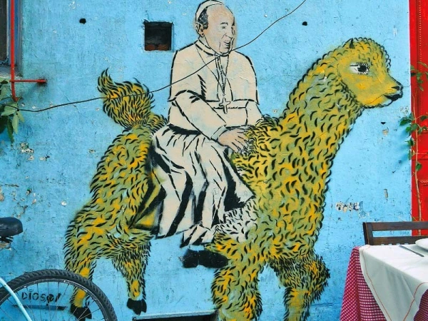 Buntes Gemälde eines Bischofs an einer blauen Hauswand