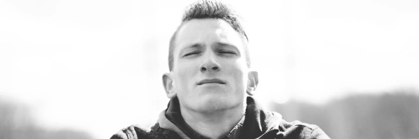 Junger Mann sitzt mit geschlossenen Augen, er scheint konzentriert zu sein.