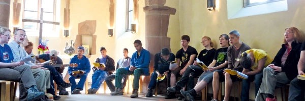 Menschen sitzen in einer Kapelle und singen