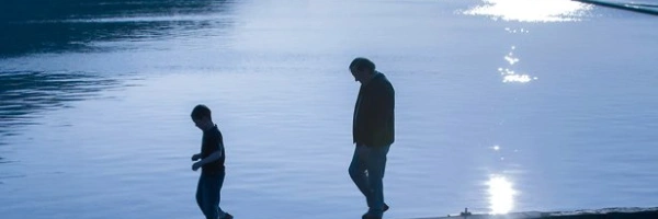 Zimzum – Zwei Menschen auf einer niedrigen Mauer umgeben von Wasser